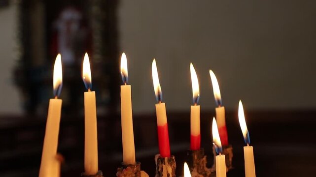Fila de velas encendidas con llama suave en ambiente oscuro