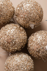 Christmas golden shiny baubles on beige background. Xmas greeting card. New Year concept. Mocha Mousse. Vertical greeting card.