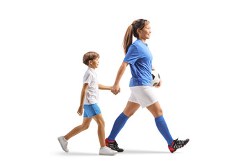 Full length profile shot of a female football player holding hand with a boy and walking
