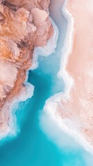 Fototapeta premium Azure water flows between pale cliffs. A sandy shore meets turquoise water with white foam. Aerial view of colorful mineral formations.