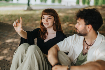 Two adults are sitting on a wooden bench in a park, engaging in a lively conversation. The lush greenery and natural outdoor setting create a warm and friendly atmosphere.