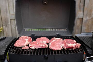 Juicy raw steaks on outdoor grill cooking preparation
