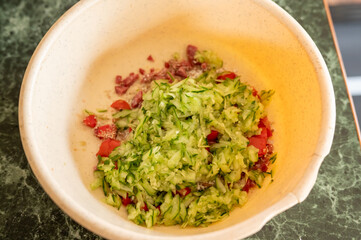 Freshly chopped vegetables in white bowl on green marble surface