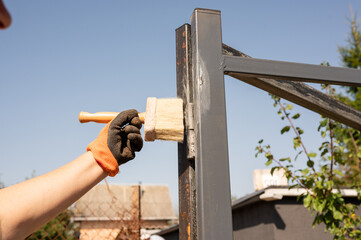 Hand painting metal structure with brush in outdoor setting