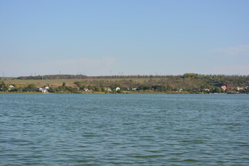 Beautiful, bright nature, landscape near the Samara River, Ukraine. Deep blue river with small waves against the background of a green bank with trees and beautiful new houses.