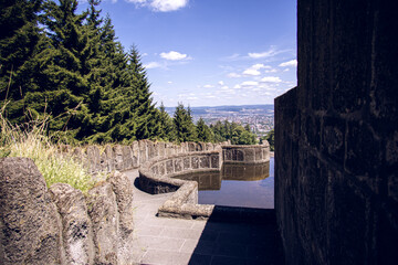 Stone terrace with water basin overlooking green forest and city view in Wilhelmshöhe park