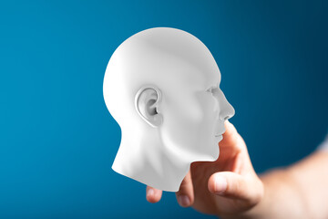 White 3D human head model held in a hand.  AI, mind, thinking, concept, technology, future, innovation, digital.