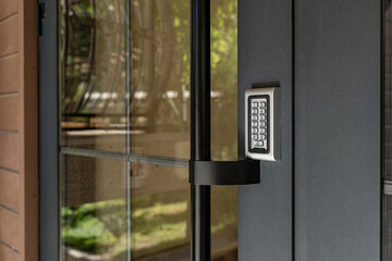 Closeup of modern door with electronic keypad access control system, secure building entrance technology.