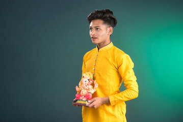 Happy young man holding and posing with Ganesha statue on the occasion of Ganesh Festival