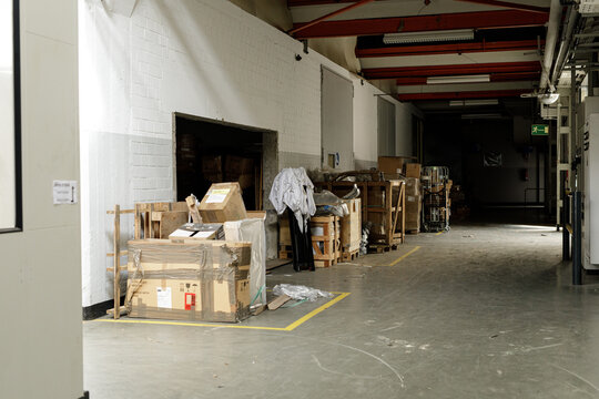 Stock photo of a messy warehouse interior with stacked cardboard boxes and pallets.