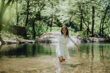 Fototapeta premium A woman dressed in white wading in a clear forest stream, surrounded by lush greenery. The atmosphere conveys peace and connection with the outdoors, making for a refreshing and vibrant scene.