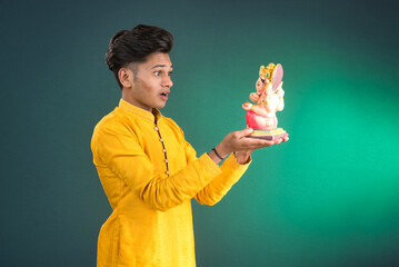 Happy young man holding and posing with Ganesha statue on the occasion of Ganesh Festival