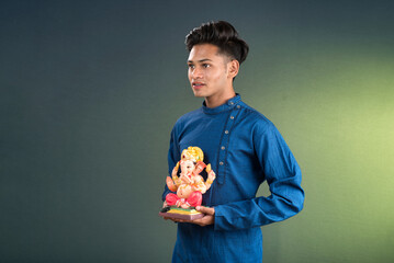 Happy young man holding and posing with Ganesha statue on the occasion of Ganesh Festival