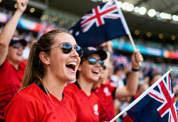 Excited female fans cheering with Australian flag at stadium, celebrating national pride and team spirit during international football match. Supporters showing enthusiasm, energy and joy in sports