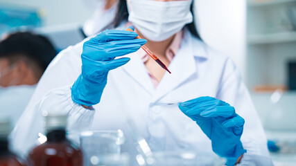Female scientist in protective gear handling a blood sample in a laboratory, representing virus testing, COVID-19 diagnostics, medical research, healthcare innovation, and scientific precision.