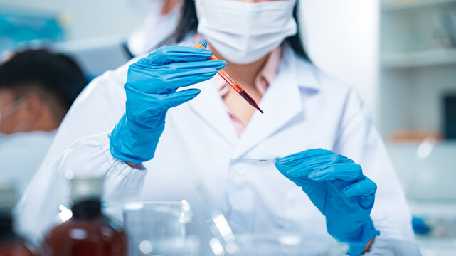 Female scientist in protective gear handling a blood sample in a laboratory, representing virus testing, COVID-19 diagnostics, medical research, healthcare innovation, and scientific precision.