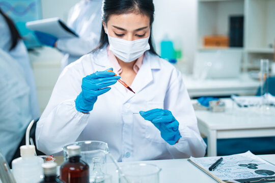Female scientist in protective gear handling a blood sample in a laboratory, representing virus testing, COVID-19 diagnostics, medical research, healthcare innovation, and scientific precision. - Powered by Adobe