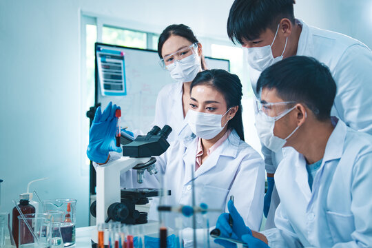 Group of scientists collaborating in a laboratory, engaging in teamwork and planning around experiments, symbolizing cooperation, diversity, and innovation in healthcare and science.