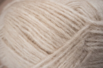 Minimalist still life featuring a yarn wrench ball in soft nude tones, set against a beige, nude, and cream background. Perfect for concepts related to handicrafts, knitting, textile work, or warm neu