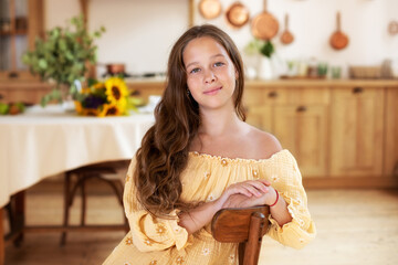 Portrait of happy teenage girl smiling looking at camera. Happy young Caucasian woman Laughing sit on chair in kitchen. Positive cute human emotion facial expression, showcasing joy and comfort.