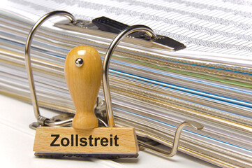 Ein Holzstempel ist beschriftet mit dem Aufdruck Zollstreit, zwischen USA, Europa und Deutschland