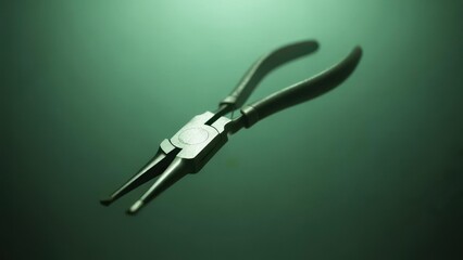 Obraz premium A pair of metallic, slender pliers rests on a reflective, teal surface, subtly lit from above, showcasing its sleek design and functional form