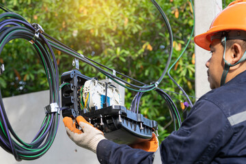 Engineer or technician checking fiber optic cables in internet splitter box.Fiber to the home...