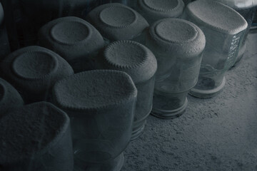 Dusty Empty Jars on Shelf in Forgotten Basement. Close-up of dusty, empty glass jars sitting untouched on an old wooden shelf in a long-abandoned basement. Perfect for themes of forgotten places.