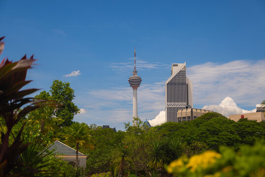 Kuala Lumpur, Malaysia &ndash; 16 September 2025: KL Tower (Menara Kuala Lumpur) and Menara Maybank rise above lush tropical trees under a blue sky with clouds, seen from a national mosques city park