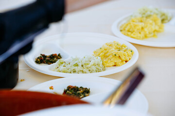 Close-up of diverse vegetable dishes on white plates at outdoor event