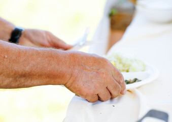 Elderly caucasian male dining outdoors holding plate and utensils