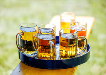Assorted beverages in glass mugs on outdoor wooden table
