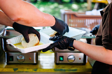 Volunteers serving meals at outdoor event with gloves and plates