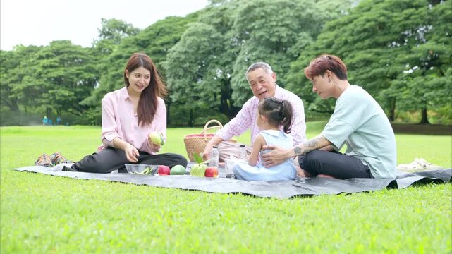 Happy multi generational Asian family enjoying picnic in the park,  Creating joyful outdoor lifestyle moment