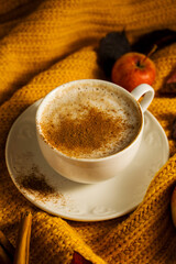 Cosy autumn coffee drink, with apples and cinnamon, orange pumpkins, wooden rustic background