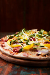 Pizza with chorizo ​​sausage, mozzarella cheese and yellow pepper. Rustic wooden background. Soft focus.	