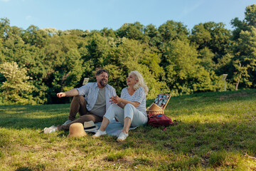 Senior couple laughing and enjoying picnic in the park