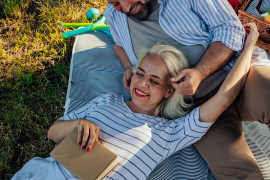 Senior couple relaxing and having fun during picnic in a park - Powered by Adobe