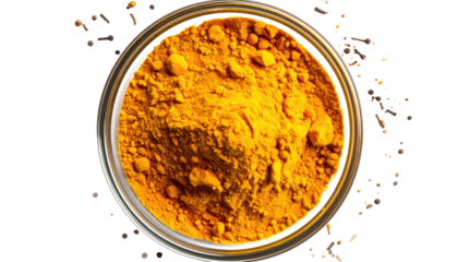 Turmeric powder in a bowl, surrounded by spices
