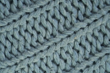 light blue texture of knitted wool silk fabric as a background, blue smooth symmetrical lines of hand-knitted needlework pattern	
