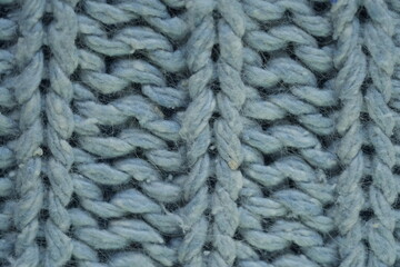 light blue texture of knitted wool silk fabric as a background, blue smooth symmetrical lines of hand-knitted needlework pattern	
