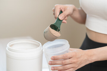 Diet meal replacement for weight loss, asian young woman in sportswear, hand in holding scoop making protein into bottle