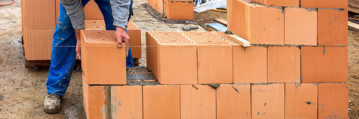 Der Rohbau von einem Wohnhaus im Neubau wird mit Ziegelsteinen gemauert, als Symbolbild für Wohnungsbau und Wohnpolitik