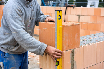 Der Rohbau von einem Wohnhaus im Neubau wird mit Ziegelsteinen gemauert, als Symbolbild für Wohnungsbau und Wohnpolitik