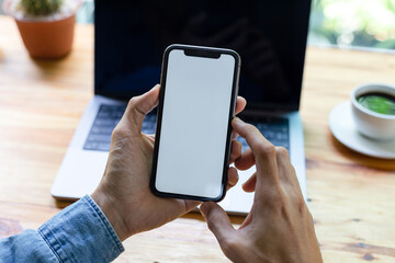 man hand using smartphone In the office Screen blank with clipping path ,Top view mockup image of male holding mobile phone with empty white screen