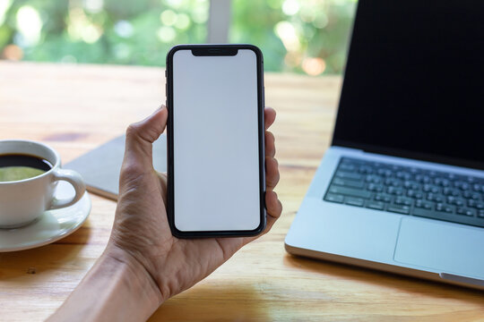 man hand using smartphone In the office Screen blank with clipping path ,Top view mockup image of male holding mobile phone with empty white screen