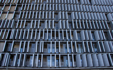 Modern architectural facade featuring a grid of balconies and metallic shading elements, showcasing innovative design and contemporary urban living aesthetics