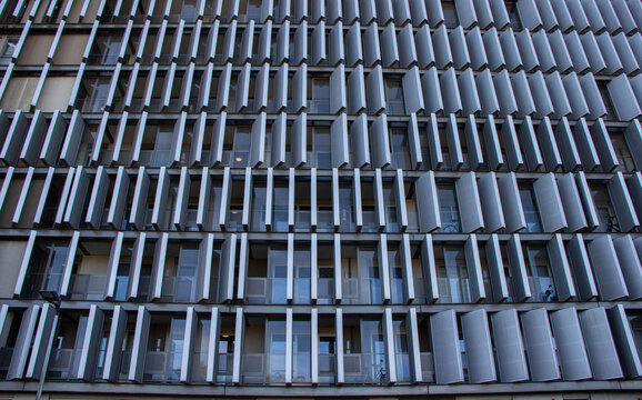 Modern architectural facade featuring a grid of balconies and metallic shading elements, showcasing innovative design and contemporary urban living aesthetics - Powered by Adobe