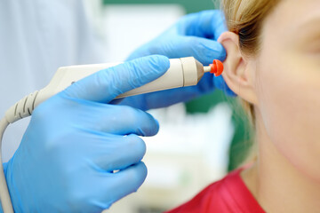 A patient is seen by an otolaryngologist. A professional ENT doctor examines a young woman’s...