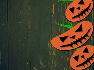 Halloween pumpkin faces on green wooden grunge background